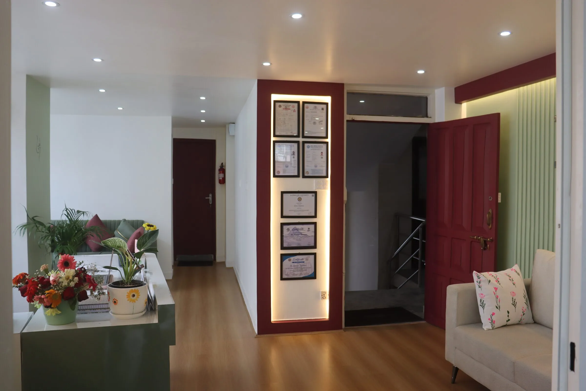 Entrance hallway with framed certificates and a green sofa